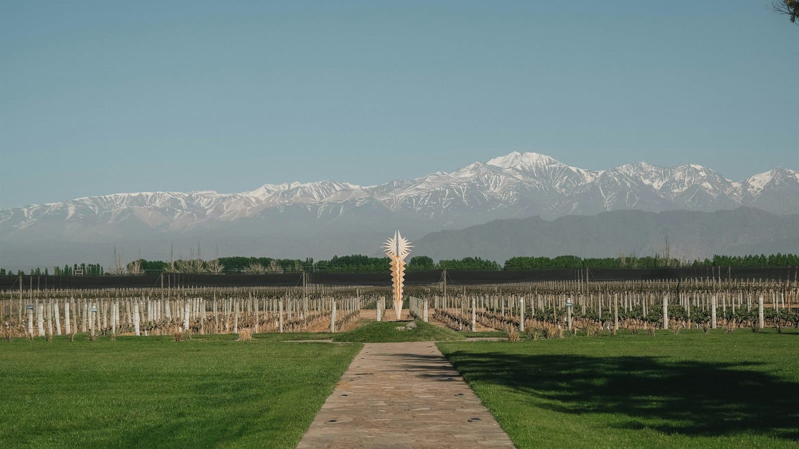 jardín mendocino con césped natural, camino de piedra y cordillera lejana